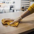side view barista cleaning table while wearing latex glove