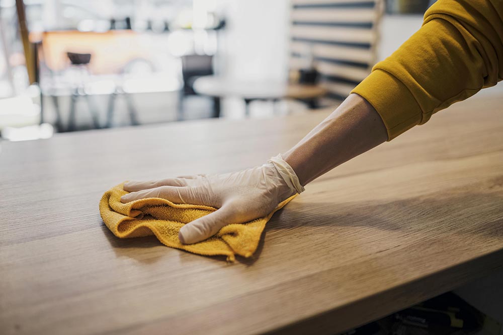 side view barista cleaning table while wearing latex glove